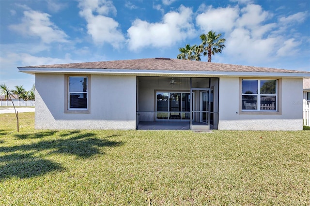 back of property featuring stucco siding, roof with shingles, a yard, and a sunroom