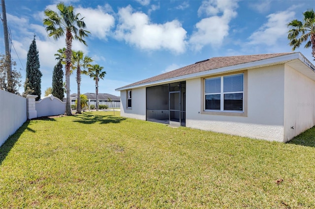 rear view of house with stucco siding, a yard, fence private yard, and a sunroom