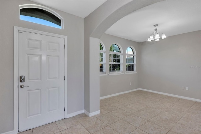 entryway with arched walkways, light tile patterned floors, baseboards, and an inviting chandelier