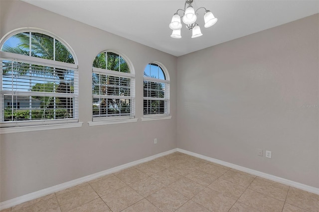 spare room with light tile patterned floors, baseboards, and an inviting chandelier