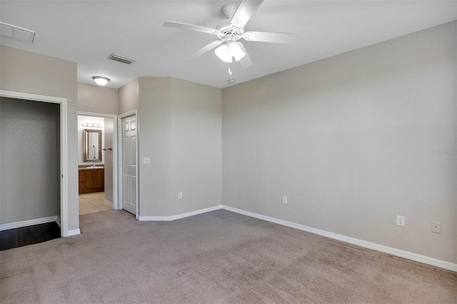 unfurnished bedroom with visible vents, light carpet, baseboards, and ensuite bath