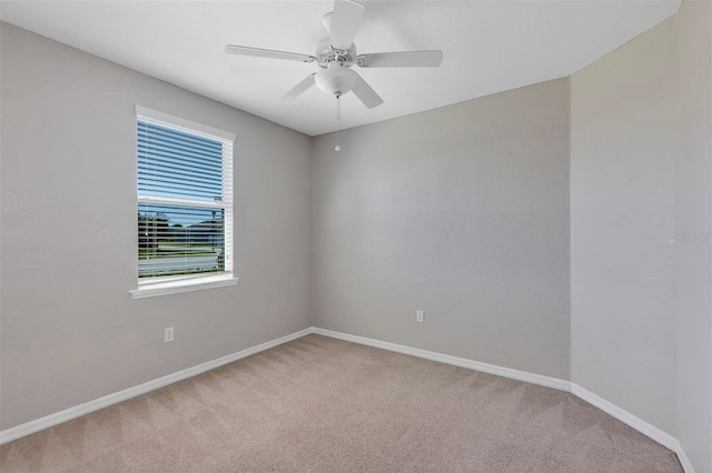 empty room with light colored carpet, baseboards, and ceiling fan