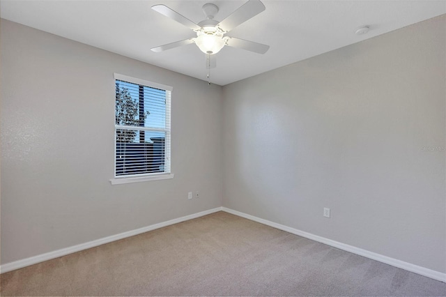 carpeted spare room with a ceiling fan and baseboards