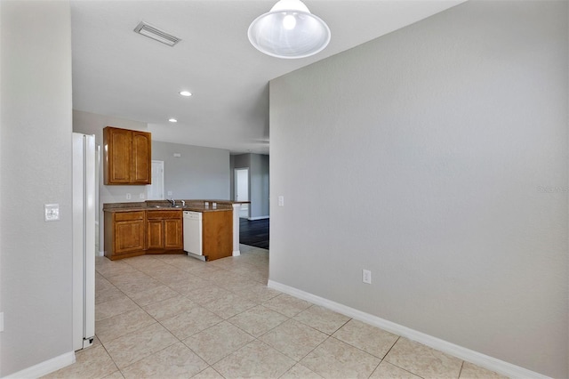 kitchen with visible vents, brown cabinets, a peninsula, white appliances, and a sink