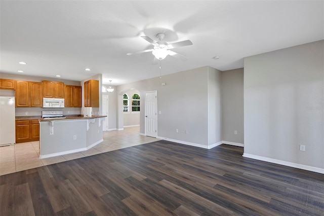 kitchen featuring white appliances, wood finished floors, a ceiling fan, recessed lighting, and open floor plan