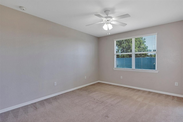 unfurnished room with light colored carpet, baseboards, and ceiling fan