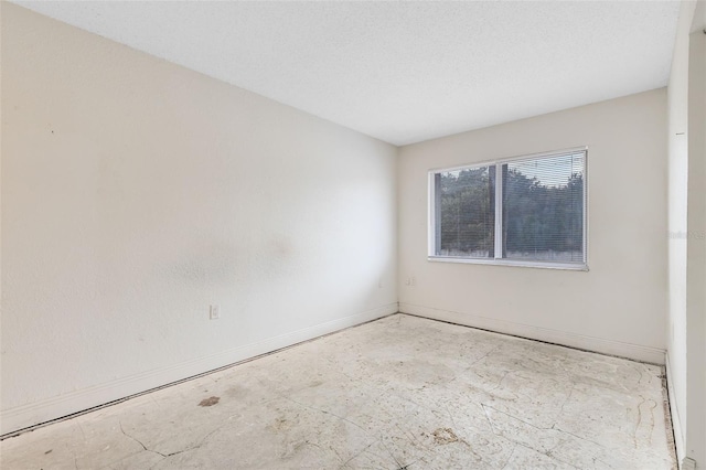 spare room featuring a textured ceiling and baseboards