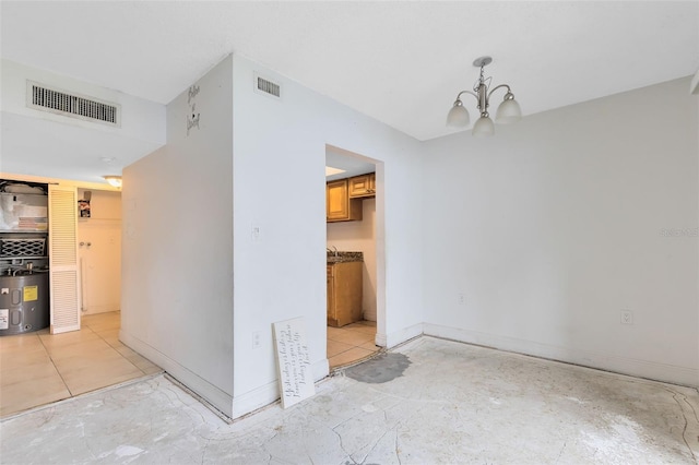 unfurnished dining area featuring visible vents, baseboards, an inviting chandelier, and water heater