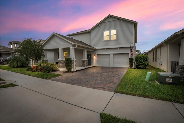 view of front of property featuring decorative driveway, a yard, an attached garage, and stucco siding