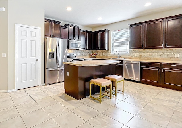 kitchen with a center island, light countertops, appliances with stainless steel finishes, a sink, and dark brown cabinetry