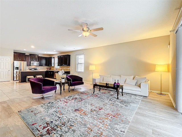 living area featuring ceiling fan, light wood-style floors, recessed lighting, and baseboards