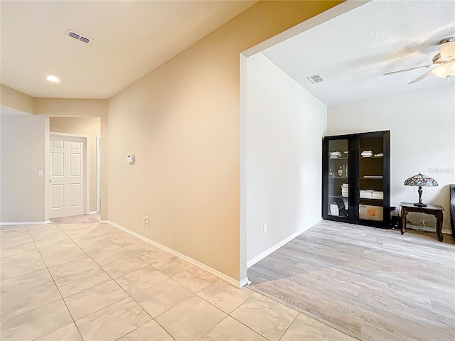 corridor featuring light wood-style floors, baseboards, and visible vents