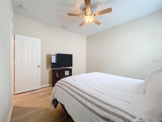 bedroom with light wood-type flooring, visible vents, ceiling fan, and baseboards