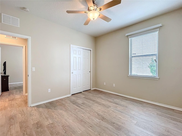 unfurnished bedroom featuring baseboards, visible vents, ceiling fan, a textured ceiling, and light wood-type flooring