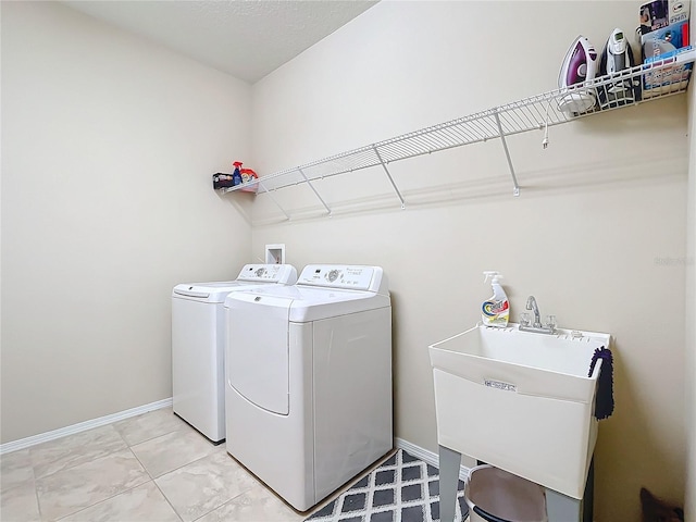 laundry area with laundry area, baseboards, independent washer and dryer, and a sink