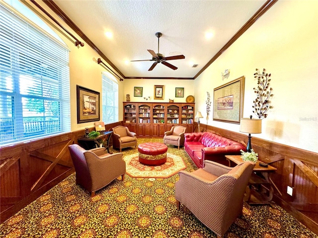 living area featuring a wainscoted wall, ornamental molding, a textured ceiling, and visible vents