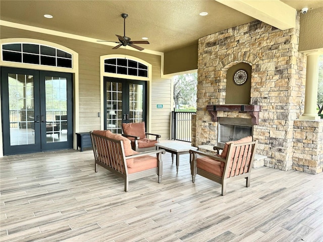 exterior space with french doors, an outdoor living space with a fireplace, and a ceiling fan