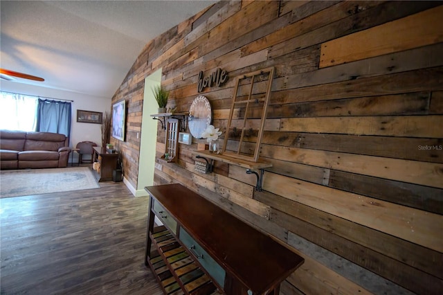 hallway featuring lofted ceiling, a textured ceiling, and wood finished floors