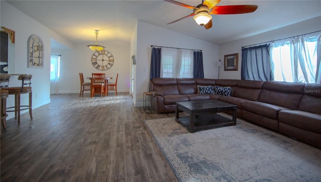 living room featuring dark wood-type flooring, vaulted ceiling, baseboards, and ceiling fan