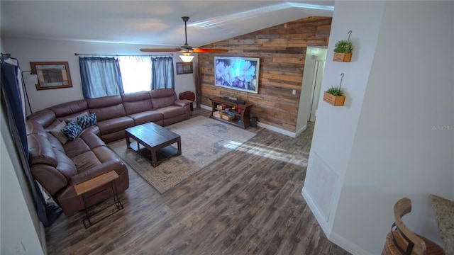 living area with ceiling fan, vaulted ceiling, wood walls, wood finished floors, and baseboards