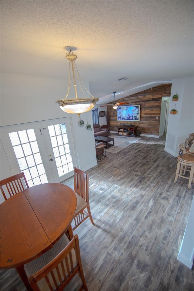 dining space featuring a textured ceiling, french doors, wood finished floors, and lofted ceiling