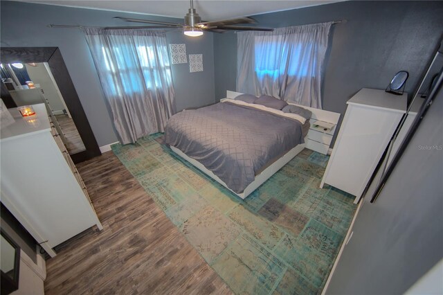 bedroom with ceiling fan, baseboards, and wood finished floors