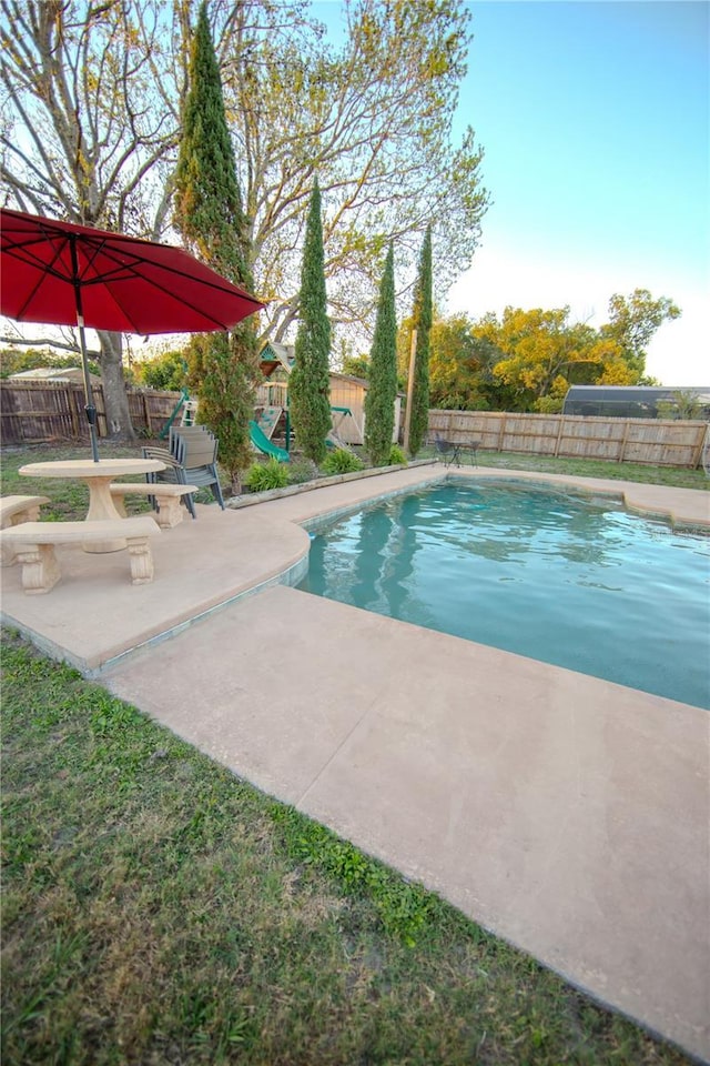 view of swimming pool featuring a patio area, a playground, and a fenced backyard