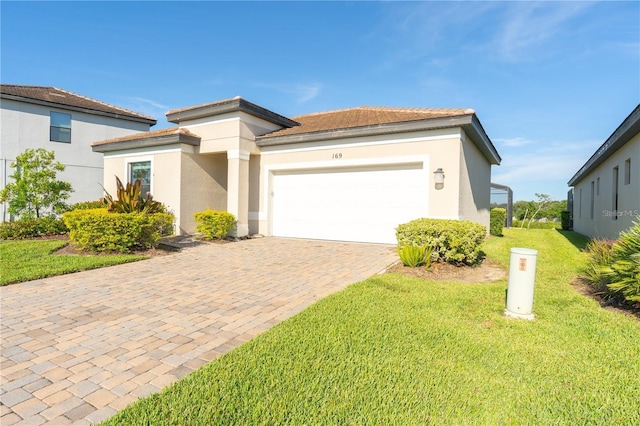 prairie-style home with a garage, a front lawn, decorative driveway, and stucco siding