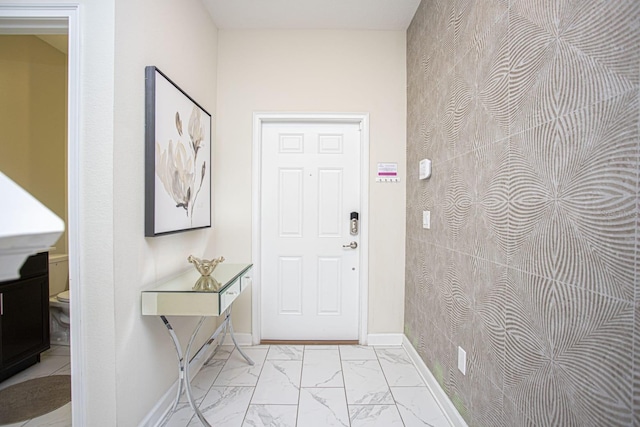 foyer featuring marble finish floor and baseboards