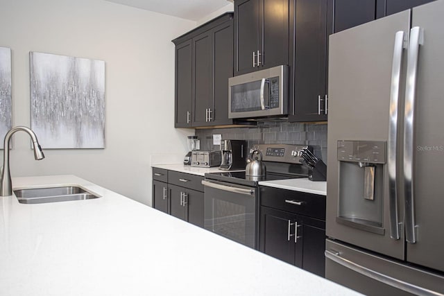 kitchen featuring backsplash, appliances with stainless steel finishes, light countertops, and a sink