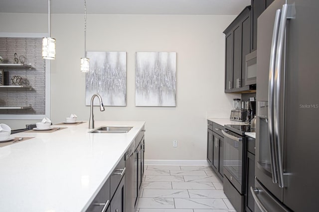 kitchen with appliances with stainless steel finishes, decorative light fixtures, marble finish floor, light countertops, and a sink
