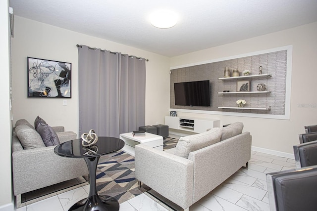 living area featuring marble finish floor, baseboards, and a textured ceiling