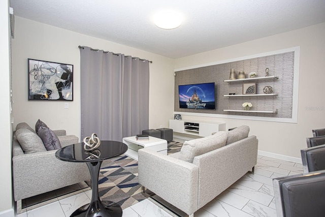 living area featuring marble finish floor, a textured ceiling, and baseboards