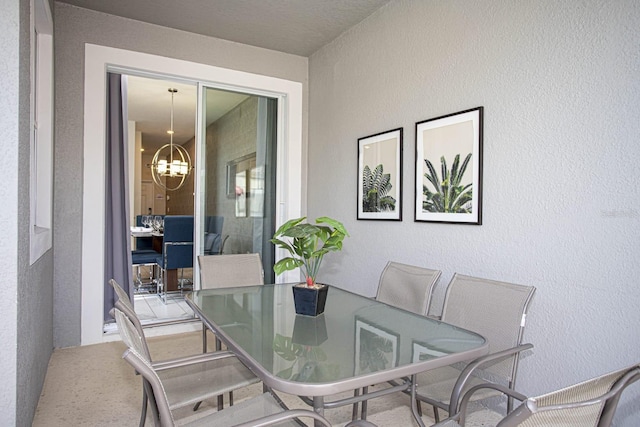 dining space with a chandelier and a textured wall
