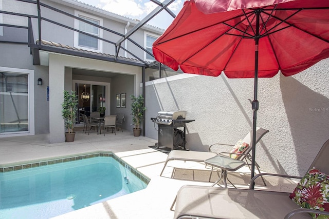 view of pool featuring glass enclosure, a patio area, and a grill