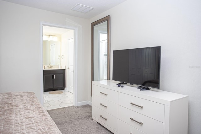 bedroom featuring visible vents, a sink, light carpet, and ensuite bathroom