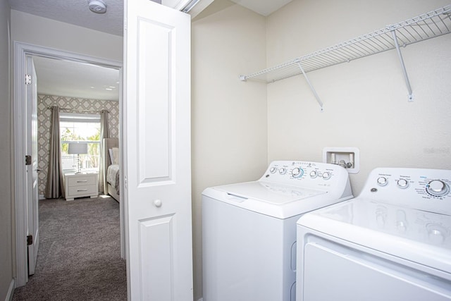 clothes washing area featuring dark carpet, independent washer and dryer, laundry area, and wallpapered walls