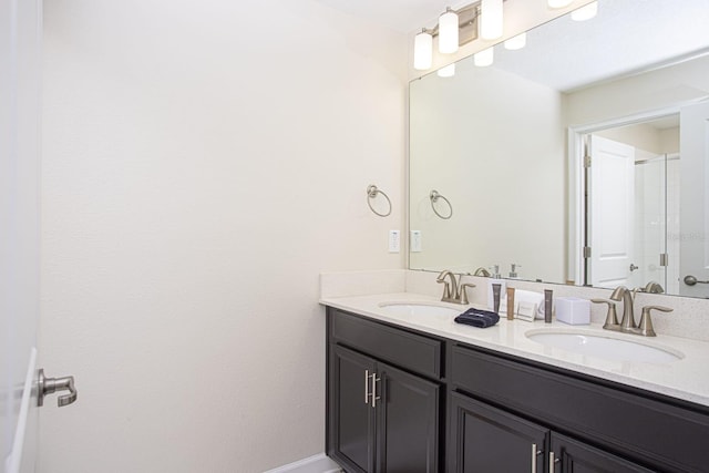 bathroom with double vanity, a sink, and baseboards