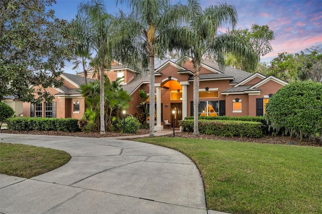 view of front of property with concrete driveway, a lawn, and stucco siding