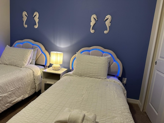 bedroom with dark carpet and baseboards