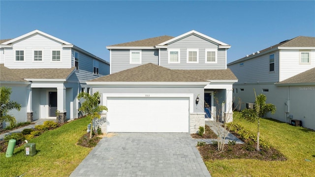 traditional-style house featuring decorative driveway, roof with shingles, and a front lawn