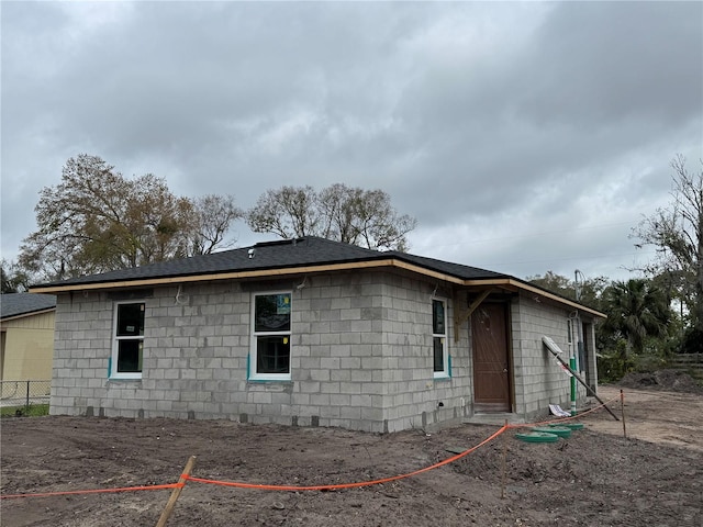 view of side of home featuring fence and roof with shingles