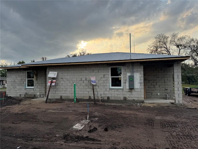 back of property at dusk featuring concrete block siding