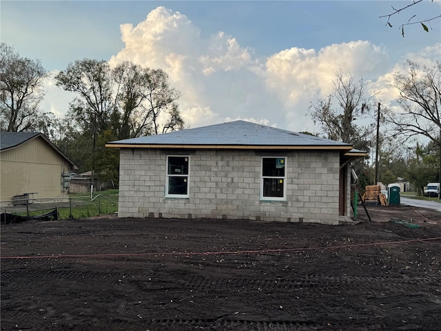 view of side of home with concrete block siding and fence