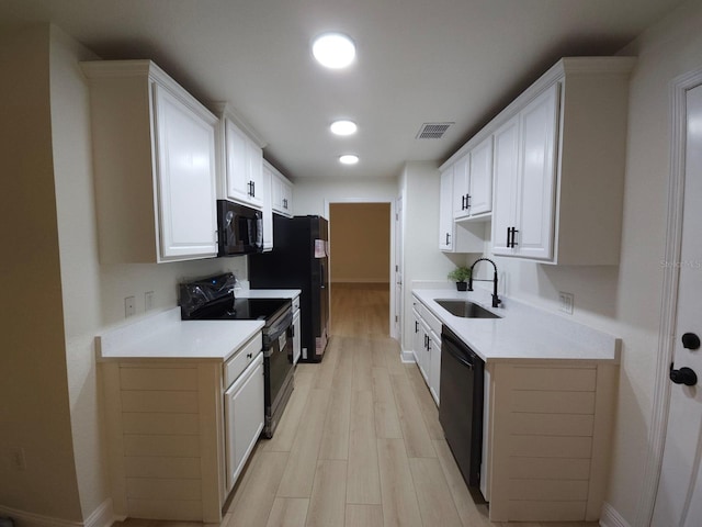 kitchen with a sink, visible vents, white cabinets, light countertops, and black appliances