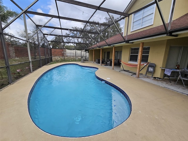 outdoor pool featuring a patio area, glass enclosure, and fence