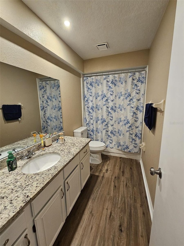 full bathroom with a textured ceiling, toilet, wood finished floors, visible vents, and vanity