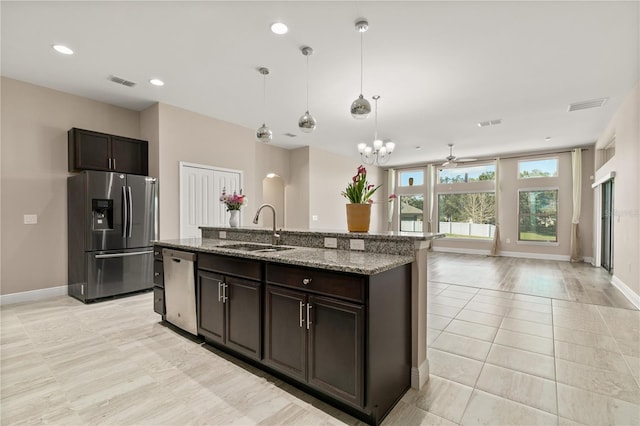 kitchen featuring a kitchen island with sink, stainless steel appliances, a sink, visible vents, and light stone countertops