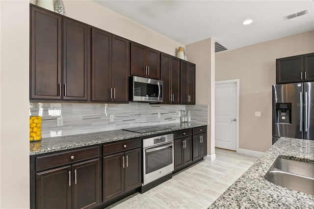 kitchen featuring light stone countertops, visible vents, appliances with stainless steel finishes, and backsplash