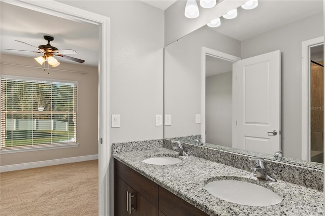 full bath with double vanity, a sink, a ceiling fan, and baseboards